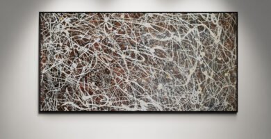 Number 15 – Jackson Pollock Style Brown Abstract Canvas displayed under spotlights, highlighting its elegant white, sand, and black splashes over a brown background