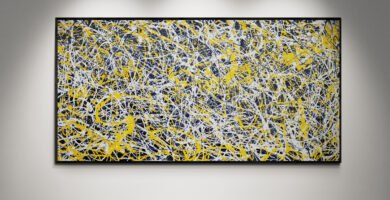 Framed abstract yellow and white Jackson Pollock-style painting displayed on a gallery wall under spotlights, showcasing vibrant energy