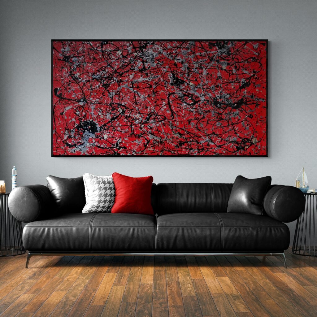 Number 12 red abstract canvas art adorning a living room with a large black leather sofa, hardwood flooring, and bold accents