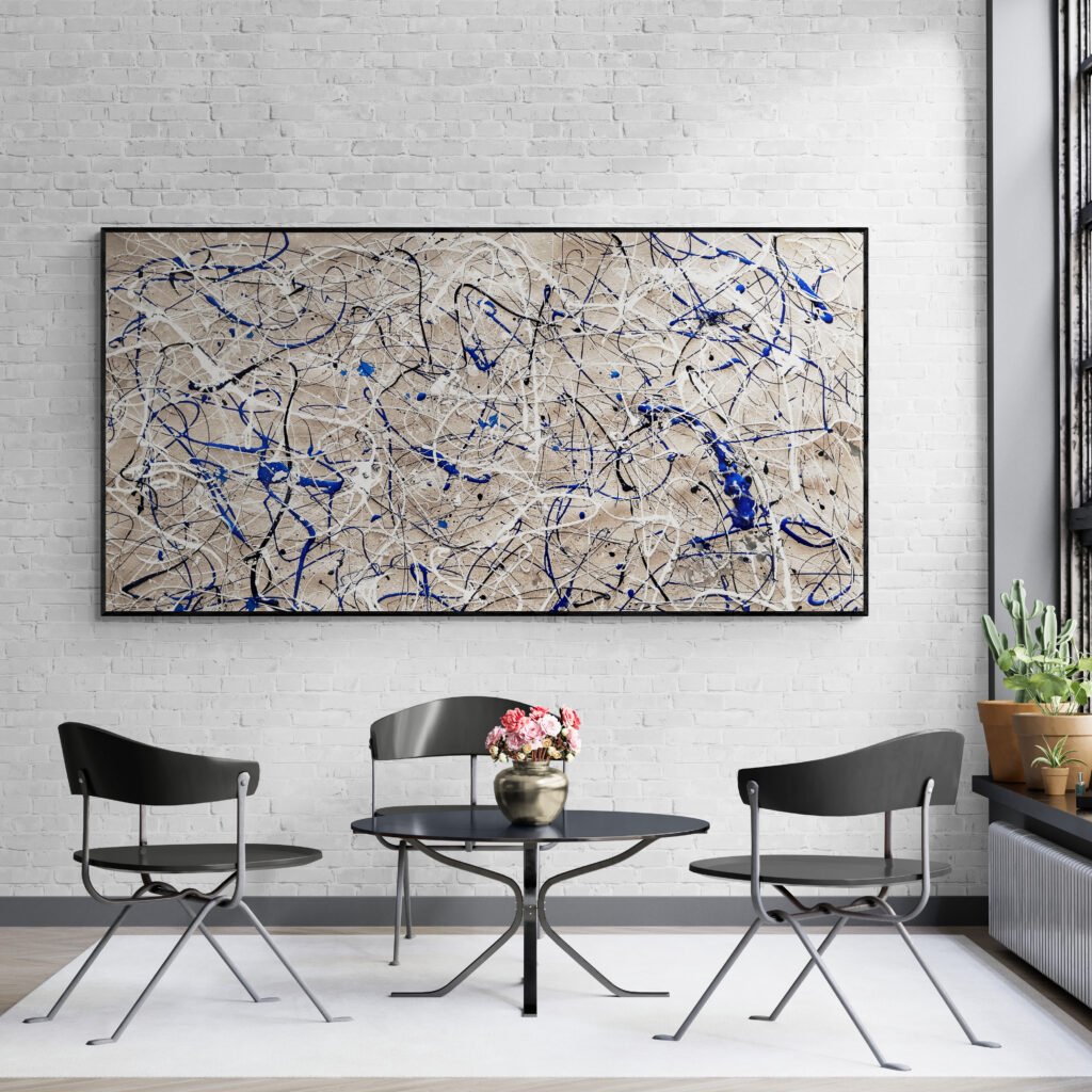 Striking Jackson Pollock style painting in sand, blue, and white, showcased on a white brick wall in a bright modern sunroom with black chairs.